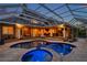 Backyard pool area with covered patio, outdoor kitchen, and lounge seating at twilight at 2280 Mackenzie Ct, Clearwater, FL 33765