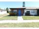 Well-maintained single story home featuring a blue front door, red brick, and lush green lawn at 24862 Us Highway 19 N # 2801, Clearwater, FL 33763