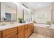 Bright bathroom features double sinks, soaking tub, and a window with shutters at 2665 Lakebreeze N Ln, Clearwater, FL 33759