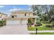 Home featuring a beige exterior, paver driveway, three-car garage and manicured landscaping at 2665 Lakebreeze N Ln, Clearwater, FL 33759