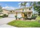Inviting front exterior with three-car garage, lush landscaping, and a welcoming entryway at 2665 Lakebreeze N Ln, Clearwater, FL 33759
