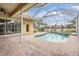 Screened-in pool boasts brick patio with a covered area, ceiling fan and lovely views of the backyard and water at 2665 Lakebreeze N Ln, Clearwater, FL 33759