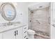 Modern bathroom with tiled shower, pebble floor, white vanity, and round mirror at 269 Algiers Dr, Venice, FL 34293