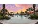 Resort-style pool with lounge chairs, umbrellas, and lush landscaping under a colorful sky at 29845 Imperati Blvd, Wesley Chapel, FL 33543