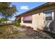 Side view of a single-story tan house with dark red trim on windows and awnings at 4002 W Gray St, Tampa, FL 33609