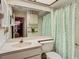 Neutral-toned bathroom featuring a large mirror, vanity, toilet, and shower with leafy green curtain at 4955 Grist Mill Cir, New Port Richey, FL 34655