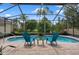 Enclosed pool with brick patio, two chairs, and a small table, surrounded by lush greenery and trees at 5140 Eclipse Ct, Spring Hill, FL 34607