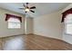 Spacious bedroom with wood-look floors, ceiling fan, and natural light from the two windows at 5210 Gato Del Sol Cir, Wesley Chapel, FL 33544