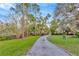 Long driveway lined with chain link fence and mature trees, enhancing curb appeal at 7201 Hodgewood Ct, Tampa, FL 33614
