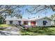 Quaint single-story house featuring a white tile roof, boat trailer and an outdoor garage with a red door at 120 Carlyle Cir, Palm Harbor, FL 34683