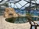 Screened-in pool with a rock waterfall, slide, and spa along with patio at 19109 Gulf Blvd, Indian Shores, FL 33785