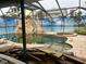Screened-in pool with a rock waterfall, slide, and spa in need of cleaning at 19109 Gulf Blvd, Indian Shores, FL 33785