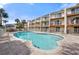 Community pool with sun loungers and white picket fence in front of multi-story condos against a blue sky at 19651 Gulf Blvd # A6, Indian Shores, FL 33785
