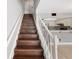 Wooden staircase with white railings, connecting to an open-concept living area with kitchen at 19651 Gulf Blvd # A6, Indian Shores, FL 33785