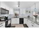 Well-lit kitchen featuring black appliances, granite countertops, white cabinetry, and tile floors at 2009 Sheffield Ct, Oldsmar, FL 34677