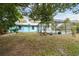 Backyard featuring blue house exterior, pool enclosure, and mature trees at 22002 Darley Pl, Land O Lakes, FL 34639