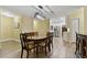 Open-concept dining area with wooden table, chairs with patterned cushions, and a view into the modern white kitchen at 22002 Darley Pl, Land O Lakes, FL 34639