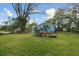 Expansive lawn with mature trees surrounding a lovely blue home, showcasing a peaceful outdoor setting at 22002 Darley Pl, Land O Lakes, FL 34639
