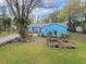 Front yard view of well-maintained lawn, mature trees, and charming blue one-story house at 22002 Darley Pl, Land O Lakes, FL 34639