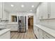 Modern kitchen with white cabinets, stainless steel refrigerator, quartz countertops, and wood-look flooring at 22002 Darley Pl, Land O Lakes, FL 34639