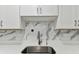 Close-up of a kitchen sink with a modern faucet, white quartz countertops, and a marble backsplash at 22002 Darley Pl, Land O Lakes, FL 34639