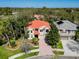 Stunning two-story home featuring a red tile roof, brick paver driveway, manicured landscaping, and mature palm trees at 2354 Messenger Cir, Safety Harbor, FL 34695