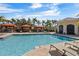 Community pool surrounded by lush landscaping, palm trees, cabanas, and lounge chairs at 2709 Via Cipriani # 532B, Clearwater, FL 33764