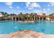 Expansive community pool and clubhouse with beautiful water feature, palm trees, and plenty of seating under bright blue skies at 2709 Via Cipriani # 532B, Clearwater, FL 33764