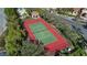 Aerial view of a well-maintained tennis court surrounded by a black fence and mature trees at 2709 Via Cipriani # 532B, Clearwater, FL 33764