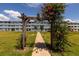 Lush green lawn with sidewalk leading to the apartment building through a wooden archway at 4715 Bay Ne St # 323, St Petersburg, FL 33703