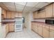 Traditional kitchen featuring wood cabinets, white appliances, and a white tile floor at 4715 Bay Ne St # 323, St Petersburg, FL 33703