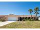 Charming single-story home with arched entryway, two-car garage, and mature palm trees at 736 Flamingo Dr, Apollo Beach, FL 33572