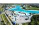 Stunning aerial view of community lagoon featuring a volleyball court, lounge area, and clear turquoise water at 9119 Forge Breeze Loop, Wesley Chapel, FL 33545