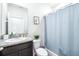 Bathroom features granite countertop, framed mirror, toilet with plant accent and shower with blue curtain at 9119 Forge Breeze Loop, Wesley Chapel, FL 33545