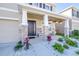 A welcoming front exterior featuring stone accents, a charming porch, and colorful hanging flower baskets at 9119 Forge Breeze Loop, Wesley Chapel, FL 33545
