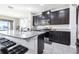 A modern kitchen with dark cabinets, stainless steel appliances, and granite countertops, adjacent to a breakfast bar with bar stools at 9119 Forge Breeze Loop, Wesley Chapel, FL 33545
