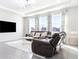Bright living room features tile flooring, large windows, and comfortable leather furniture at 9119 Forge Breeze Loop, Wesley Chapel, FL 33545