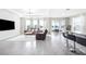 Open living room features tile floors, neutral decor, a tray ceiling, and natural light from sliding glass doors at 9119 Forge Breeze Loop, Wesley Chapel, FL 33545