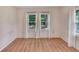 Bedroom with light wood-look floors and two windows with white curtains allowing natural light at 11718 N Ola Ave, Tampa, FL 33612