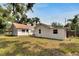 Back exterior view of the home and yard, with a light-colored exterior and traditional architecture at 11718 N Ola Ave, Tampa, FL 33612