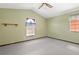 Bright bedroom has a ceiling fan, neutral carpet, olive walls, and two windows at 130 80Th Ne Ave, St Petersburg, FL 33702