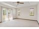 Bright main bedroom features neutral carpet, tray ceiling, fan, and access to a private balcony with outdoor views at 130 80Th Ne Ave, St Petersburg, FL 33702