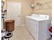 Bright laundry room with white washer and dryer, basket, and storage shelf at 1307 Garden Stone Ln, Brandon, FL 33510