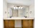 Bright bathroom featuring double sinks with wooden cabinets, a large mirror, and neutral toned walls at 19531 Deer Lake Rd, Lutz, FL 33548