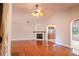 Open-concept living room with fireplace, hardwood floors, ceiling fan, and archway leading to kitchen at 19531 Deer Lake Rd, Lutz, FL 33548