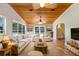 Beautifully staged sunroom with wood paneled ceiling, tile floors, comfortable seating, and views of the outdoor scenery at 19531 Deer Lake Rd, Lutz, FL 33548