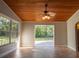 Sunroom with wood plank ceiling, ceiling fan, tile flooring, and a large glass door leading to the outdoors at 19531 Deer Lake Rd, Lutz, FL 33548