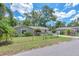 A single-story home with light-blue paint, stone accents, a fenced yard, mature trees and is located on a paved street at 2412 Giddens Ave, Seffner, FL 33584