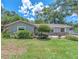 A charming single-story home with a well-maintained lawn and mature landscaping, complemented by a stone accent wall at 2412 Giddens Ave, Seffner, FL 33584