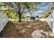 A large backyard features mature trees and white fencing and space for entertaining at 2887 North Rd, Clearwater, FL 33760